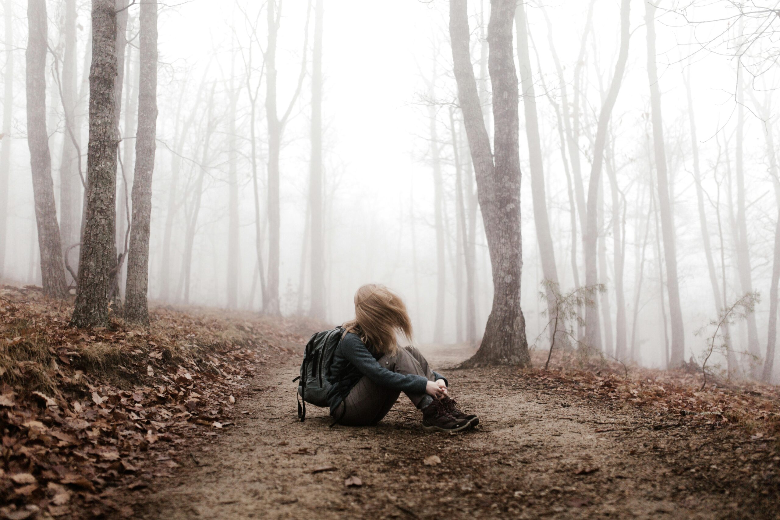 A lone hiker sits on a foggy path in Roaring Gap, NC, amidst a serene woodland setting.